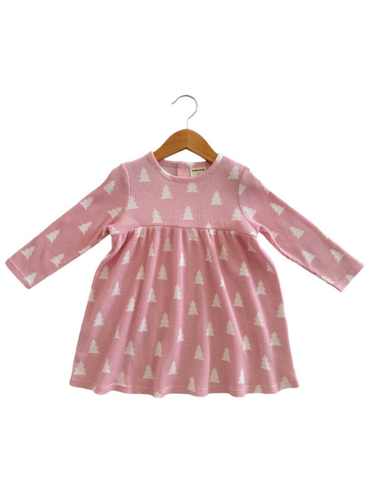 A long sleeve pink dress with a waffle texture and Christmas tree patterns, displayed on a wooden hanger.